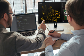 Two colleagues working on tech with computers